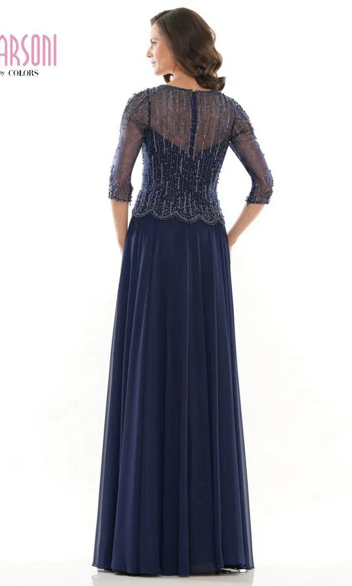 A woman faces away, wearing the Marsoni M312 long formal dress in navy blue, featuring a sheer beaded bodice with three-quarter sleeves and an elegant A-line skirt.